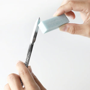 hand using fine grade sape eraser on chisel blade